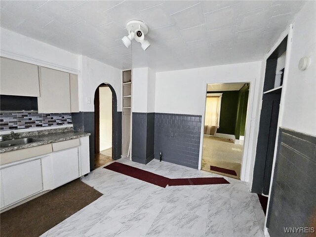 kitchen featuring white cabinets, backsplash, and sink