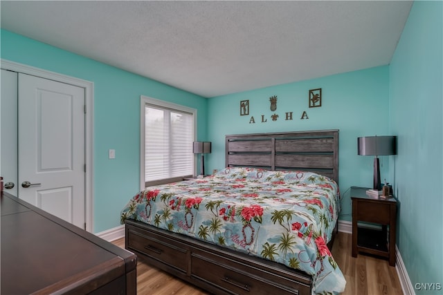 bedroom with a textured ceiling, light wood-type flooring, and a closet