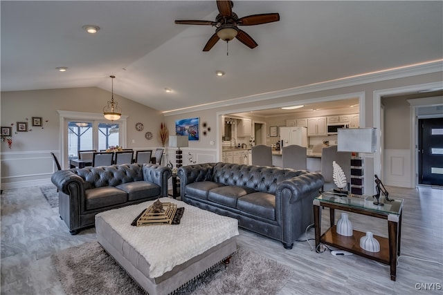 living room featuring ceiling fan, light wood-type flooring, crown molding, and vaulted ceiling