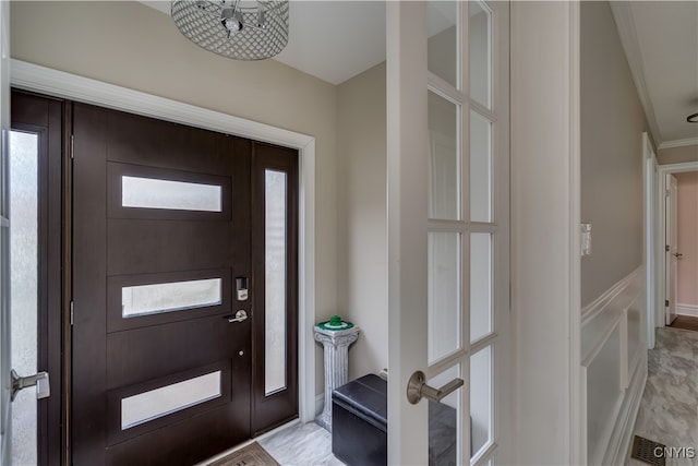 foyer featuring crown molding and a wealth of natural light