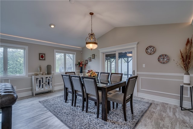 dining room featuring light wood-type flooring and vaulted ceiling