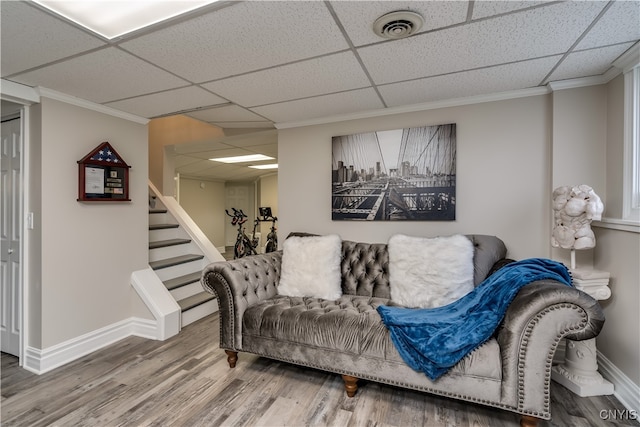 living room with wood-type flooring, a drop ceiling, and ornamental molding