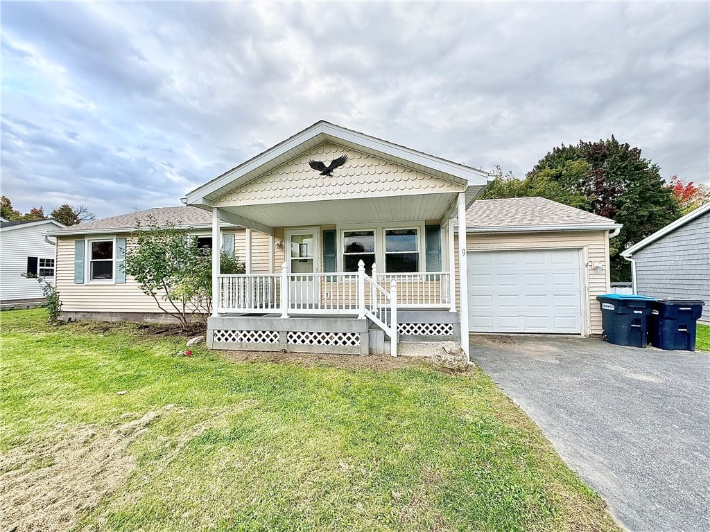 view of front of house with a garage, a front lawn, and covered porch