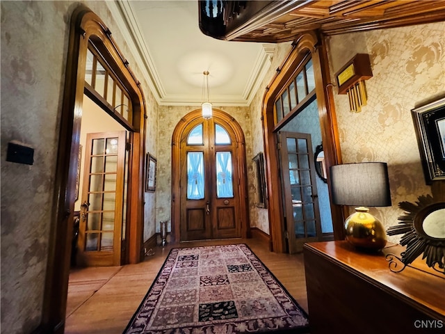 entrance foyer with french doors, crown molding, and light hardwood / wood-style floors