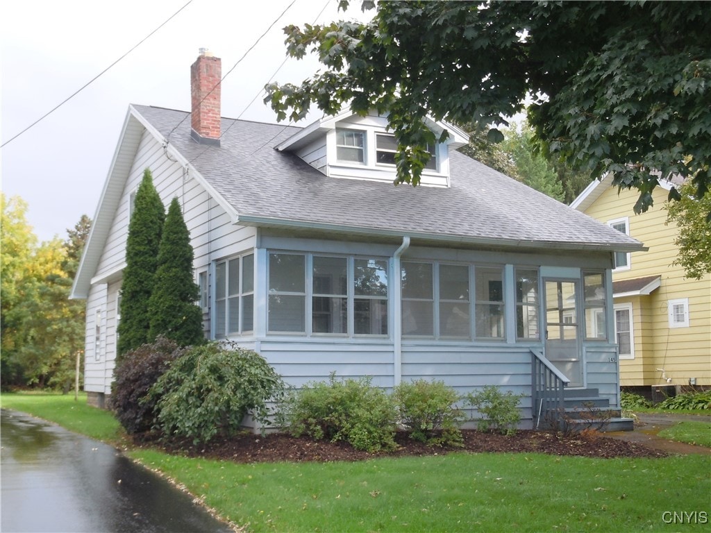 view of front of home with a sunroom and a front yard