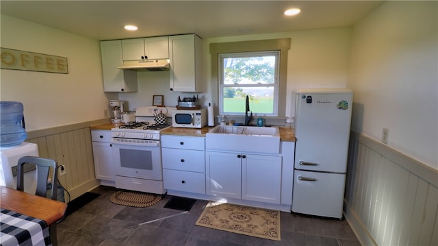 kitchen with wood counters, white appliances, sink, and white cabinetry