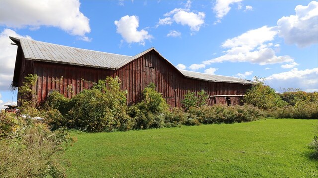 view of home's exterior with an outbuilding and a lawn