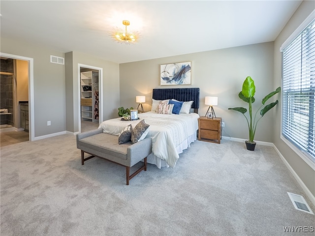 bedroom featuring light colored carpet, a walk in closet, ensuite bathroom, and multiple windows