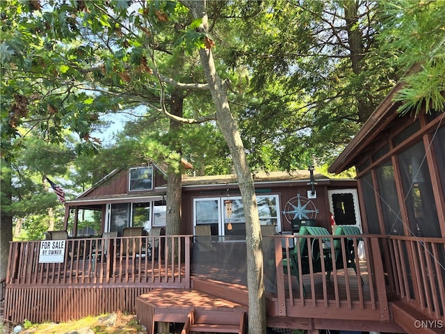 rear view of property featuring a sunroom and a wooden deck