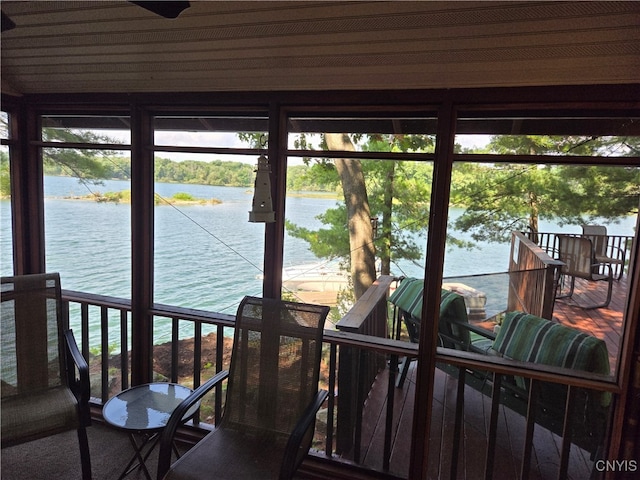 sunroom featuring a water view