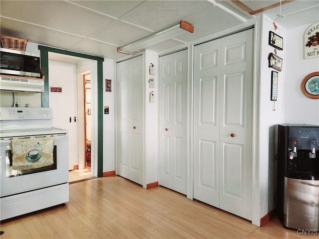 kitchen with exhaust hood, light hardwood / wood-style floors, and white range with electric stovetop