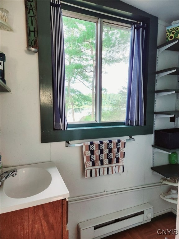 bathroom featuring plenty of natural light, baseboard heating, hardwood / wood-style flooring, and vanity