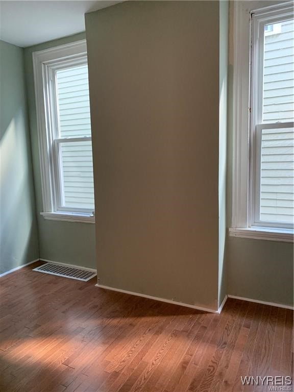 empty room with hardwood / wood-style floors and a healthy amount of sunlight