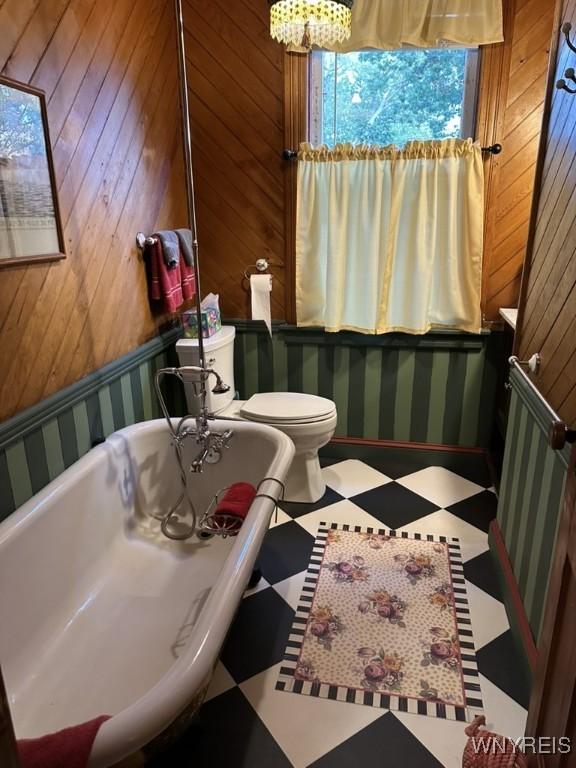 42916 St Lawrence Ave, Orleans, NY 13692 - bathroom featuring a soaking tub, tile patterned floors, wooden walls, and a chandelier