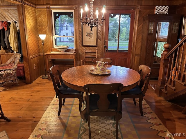 dining space featuring wood walls, hardwood / wood-style floors, and a chandelier