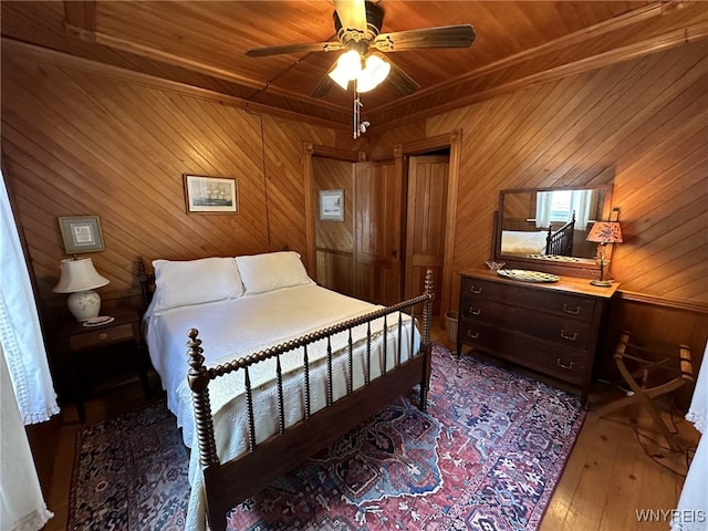 bedroom with ceiling fan, hardwood / wood-style flooring, wooden walls, and wooden ceiling