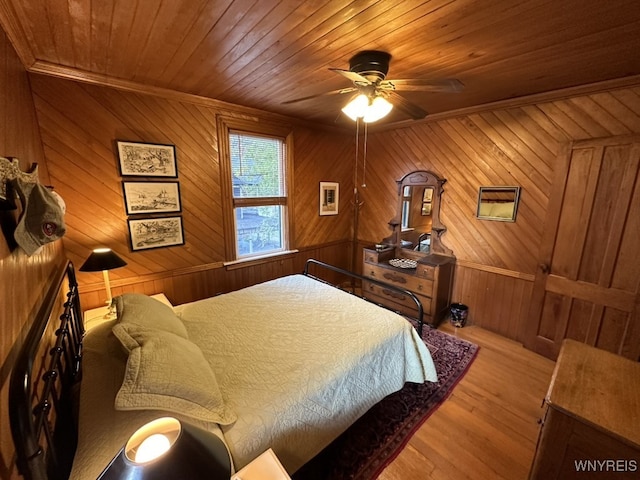 bedroom featuring light hardwood / wood-style floors, wood ceiling, wooden walls, and ceiling fan