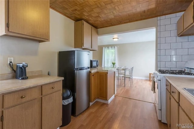 kitchen featuring light wood-type flooring, light brown cabinets, stainless steel fridge, gas range gas stove, and backsplash