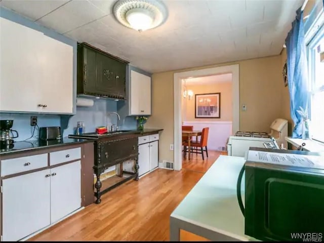 kitchen featuring white cabinets, sink, white range with gas stovetop, and light hardwood / wood-style floors