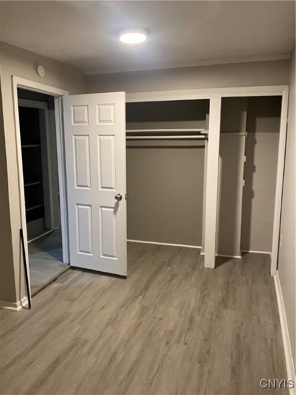 unfurnished bedroom with multiple closets and hardwood / wood-style floors