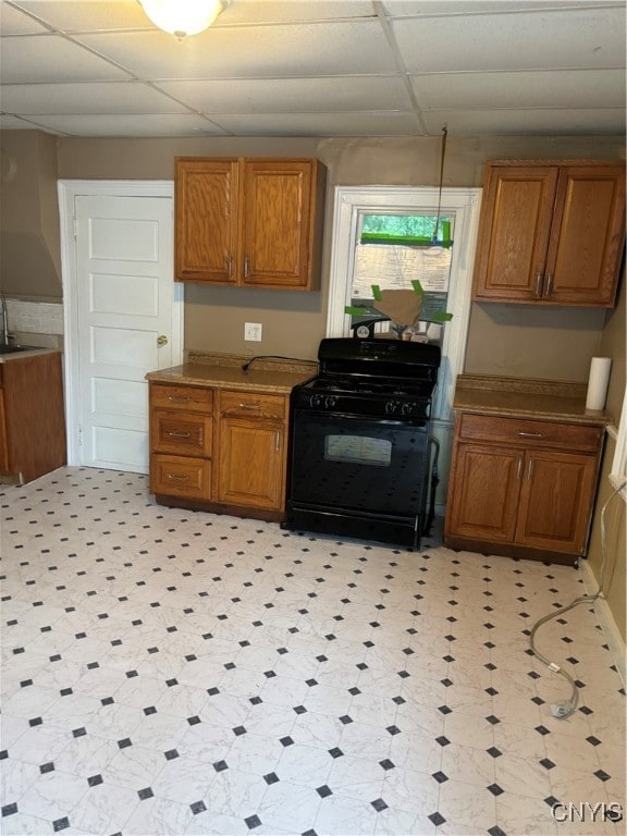 kitchen featuring black gas range oven, a drop ceiling, and sink