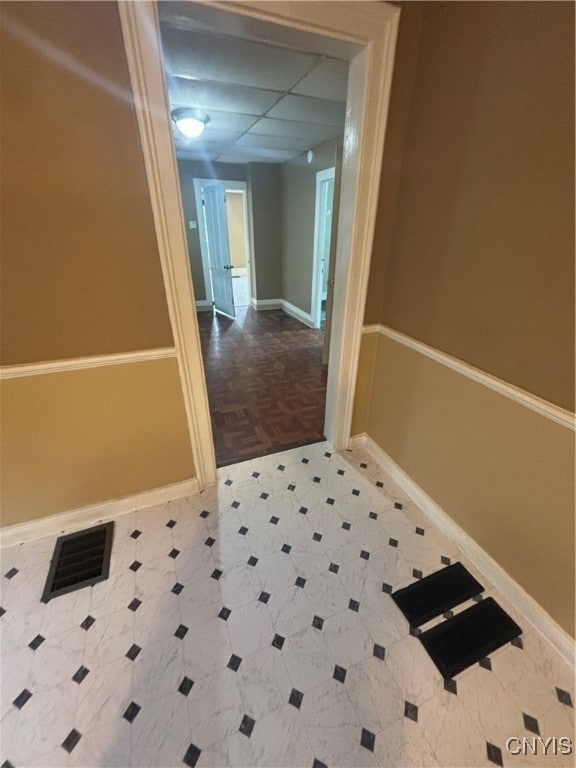 corridor with a drop ceiling and parquet floors