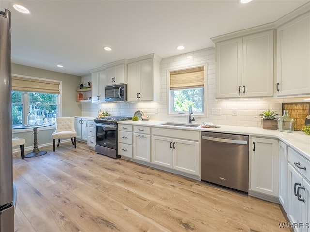 kitchen with a wealth of natural light, appliances with stainless steel finishes, and white cabinetry