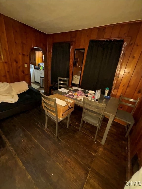 dining space with wood walls, independent washer and dryer, and dark hardwood / wood-style flooring