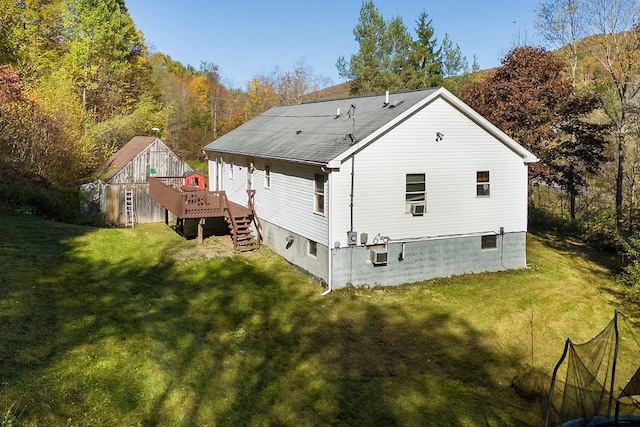 rear view of property featuring a wooden deck and a lawn