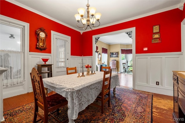 dining room featuring wood-type flooring, crown molding, and a chandelier