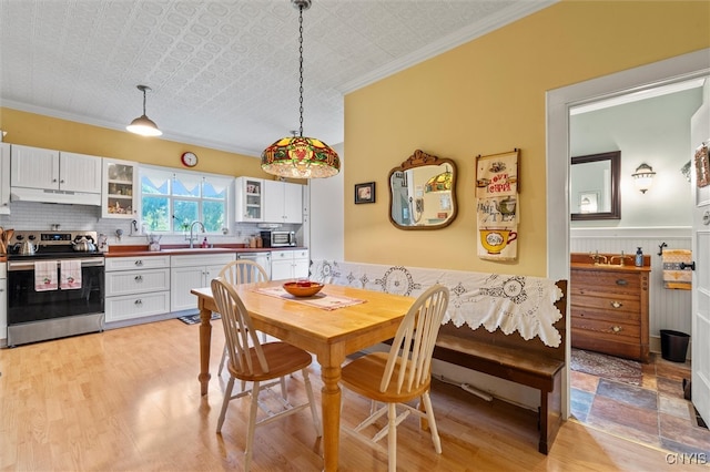 dining space featuring crown molding, sink, and light hardwood / wood-style flooring