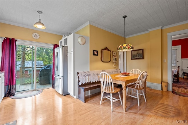 dining space with ornamental molding and light hardwood / wood-style flooring