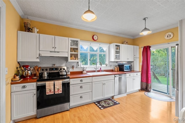 kitchen with decorative light fixtures, stainless steel appliances, sink, and white cabinetry