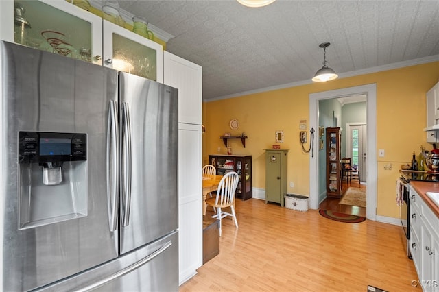 kitchen featuring stainless steel fridge, hanging light fixtures, crown molding, and white cabinetry