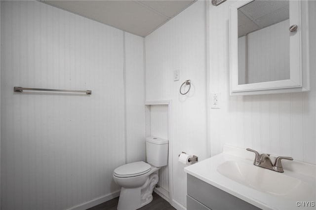 bathroom featuring vanity, toilet, and wood walls