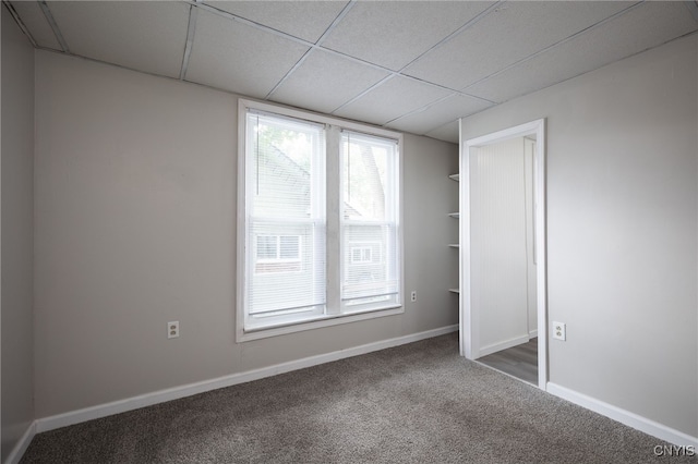 spare room featuring a drop ceiling and dark colored carpet