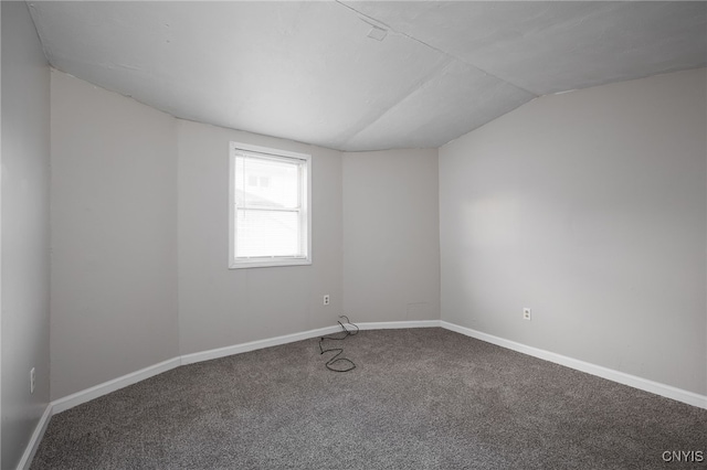 carpeted spare room with vaulted ceiling