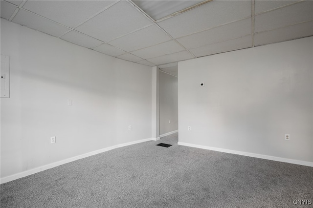 carpeted empty room featuring a drop ceiling and electric panel