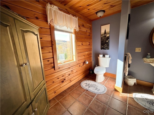 bathroom with tile patterned floors, wood ceiling, wooden walls, and toilet