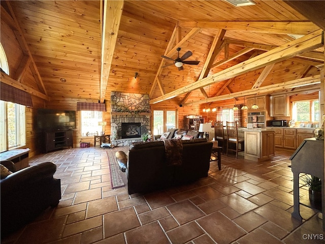 living room featuring wooden ceiling, a fireplace, a healthy amount of sunlight, and beam ceiling