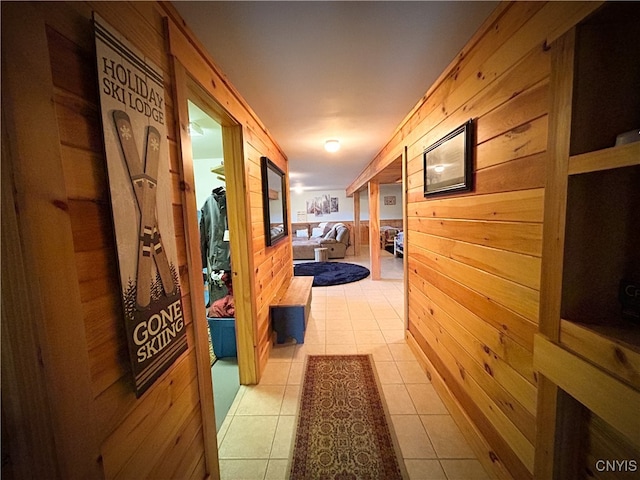 hall with wood walls and light tile patterned floors