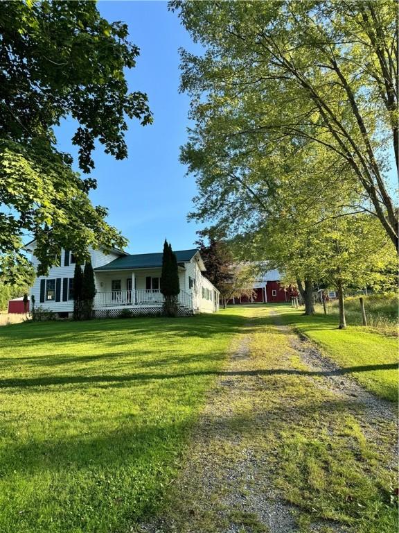 view of side of home featuring covered porch and a yard