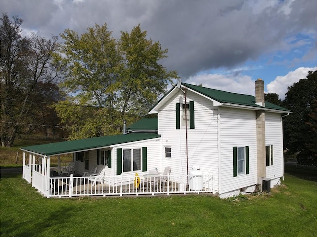 rear view of property featuring central air condition unit, a yard, and covered porch