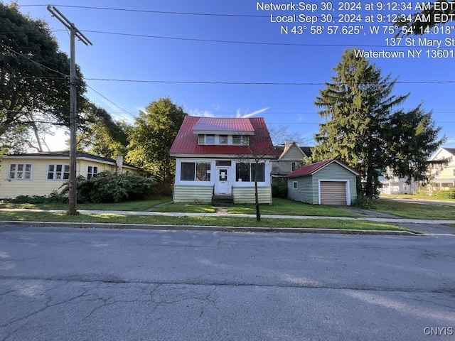 view of front facade featuring a garage, an outbuilding, and a front lawn