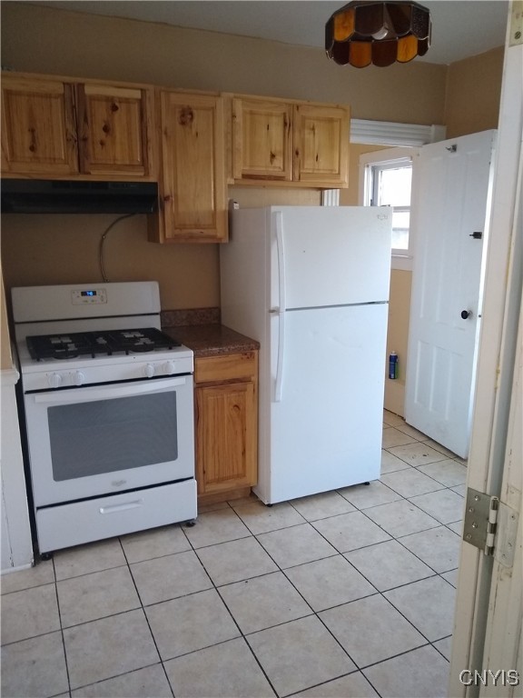 kitchen with extractor fan, white appliances, and light tile patterned floors