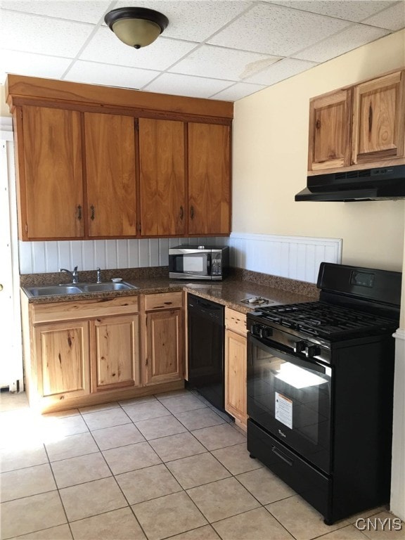 kitchen featuring a paneled ceiling, light tile patterned flooring, black appliances, and sink