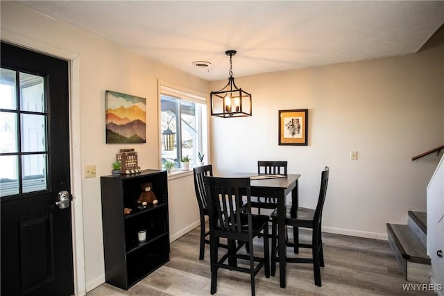 dining area with wood-type flooring and a chandelier