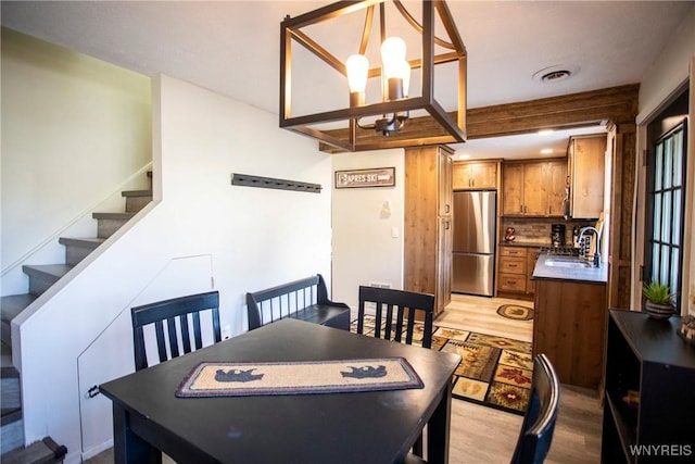 dining space with a chandelier, light hardwood / wood-style floors, and sink