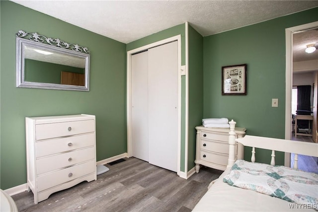 bedroom with a closet, hardwood / wood-style floors, and a textured ceiling