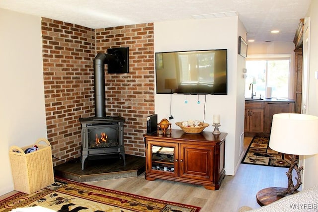 living room featuring light hardwood / wood-style floors, a wood stove, and sink